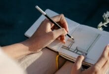 A person drawing with left hand in a notebook