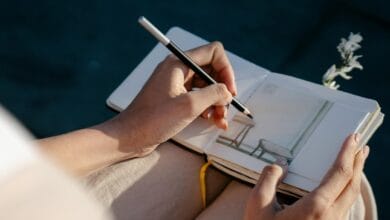 A person drawing with left hand in a notebook